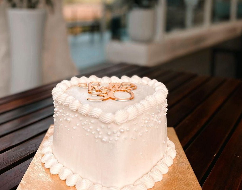 Pearled white heart cake with a gold topper, on a terrace